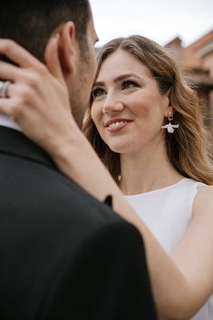 a woman in a white dress standing next to a man wearing a suit and tie