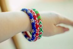 a child's hand with four bracelets on their wrist and one in the foreground