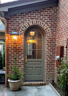 a front door with two potted plants on the side and a brick building in the background