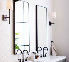 two bathroom sinks with mirrors above them in a white and black color scheme on the wall