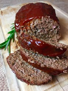 sliced meatloaf sitting on top of a wooden cutting board