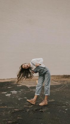 a woman is standing in the middle of an empty parking lot with her hair blowing in the wind