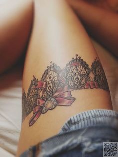 a woman's thigh with a tattoo on it and a ribbon around her ankles