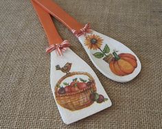 two wooden spoons with painted designs on them sitting on the floor next to each other