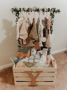 a wooden crate filled with baby clothes and other items hanging from hooks on the wall