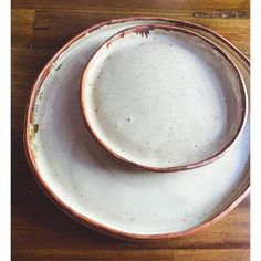 two dirty plates sitting on top of a wooden table next to each other and one is white with brown speckles