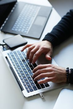 a person typing on a laptop with their hands resting on the keyboard and another persons hand