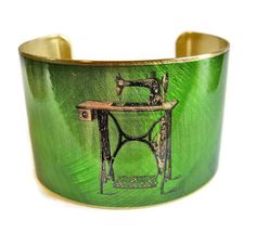 a green cuff bracelet with an image of a sewing machine on the front and side