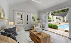 a living room filled with furniture and a swimming pool in the backround next to it