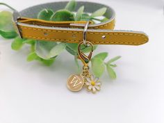 a dog collar with a monogram charm on it and a flower keychain