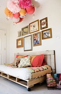 an image of a bedroom with pictures on the wall and below it is a bed made out of pallets