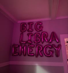 the words big library energy are lit up in pink neon letters on a purple wall