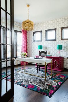 a living room with pink and green accents on the walls, black doors, and rugs