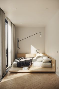 a bed sitting on top of a wooden floor next to a window