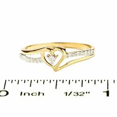 a yellow gold ring with two hearts and diamonds in the middle, on top of a ruler