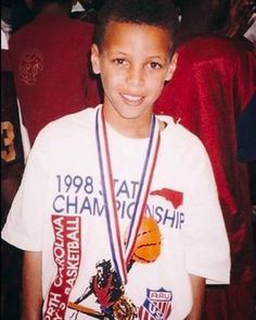 a young boy wearing a white shirt and medal around his neck