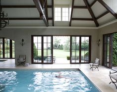 an indoor swimming pool with sliding glass doors leading to the patio area and large windows