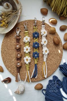 four bracelets with flowers are on a cork board next to shells and seashells