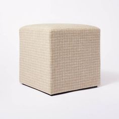 a small square ottoman sitting on top of a white floor