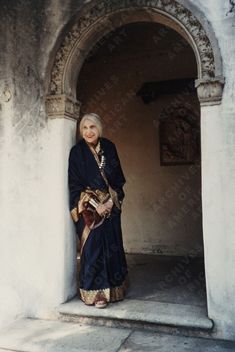 an older woman standing in front of a doorway