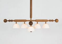 a wooden chandelier with five lights hanging from it's sides and two white glass shades