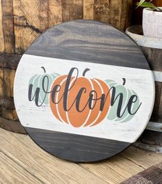 a wooden sign that says welcome with a pumpkin on it next to some wine barrels