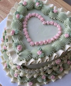 a heart shaped cake with pink and green frosting on it's sides, sitting on a white platter