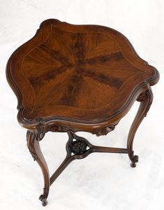 an antique wooden table with ornate carvings on the top and bottom, against a white background