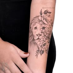 a woman's arm with a lion and flowers tattoo on it