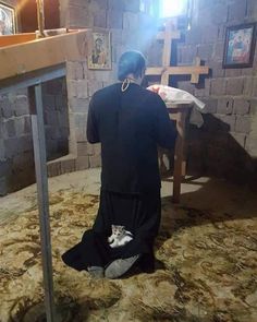 a person sitting on the floor in front of a cross