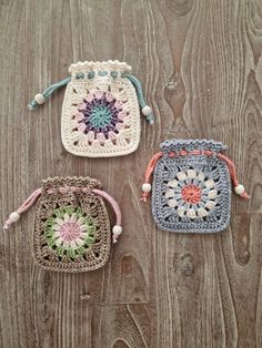 three crocheted bags sitting on top of a wooden table