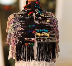 a woman's shawl with multicolored beads and fringes on it