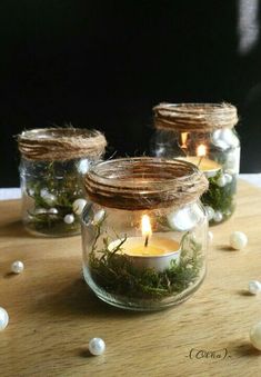 three mason jars filled with moss and lit candles