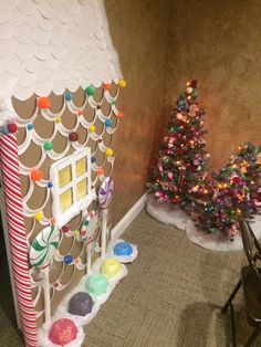 a gingerbread house decorated for christmas with candy and candies on the floor next to it