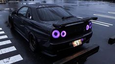 a black car with purple eyes parked on the side of the road in the rain