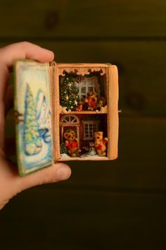 someone is holding an open miniature box with christmas decorations in it and there are teddy bears inside