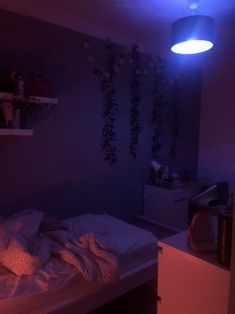 a bed in a room with purple light on the wall and plants hanging from the ceiling