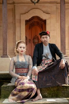 a man and woman sitting on steps in front of a building