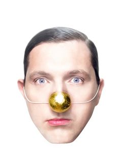 a man with a nose ring and glasses on his face is wearing a gold ball