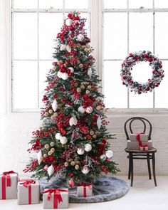 a christmas tree decorated with red and white balls, ornaments and wreaths in front of a window