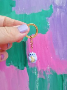 a person holding onto a keychain with a small animal on it's side