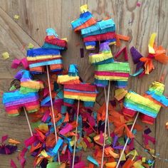 there are many colorful pinwheels on the wooden table with confetti sticks