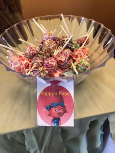 a bowl filled with lots of candy sitting on top of a table next to a sign