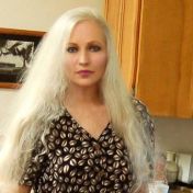 a woman with long white hair standing in a kitchen