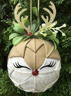 a christmas ornament hanging from a tree with antlers and leaves on it