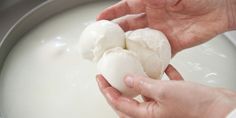 someone is peeling hard boiled eggs in a pan with milk on the side and another hand holding one