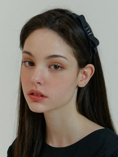 a woman with long brown hair wearing a black shirt and a bow in her hair