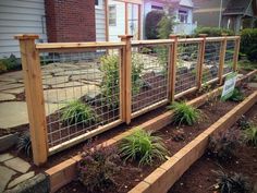 a fenced in garden area with plants growing on the ground and landscaping around it