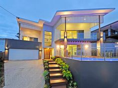 a modern house with stairs leading up to the front door and pool area at dusk