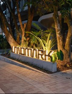 a sign that reads londonmark in front of some trees and bushes on the sidewalk